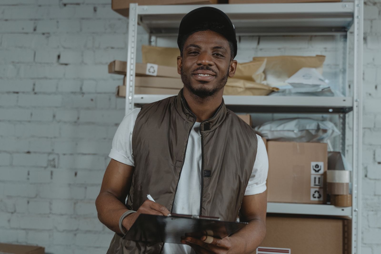 Black logistics worker checking cargo records in a warehouse